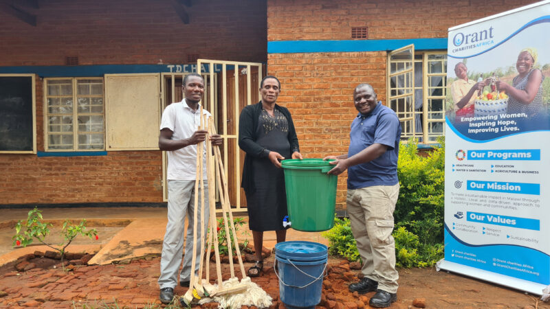 Orant staff and school administrators stand with some of the new sanitation supplies.