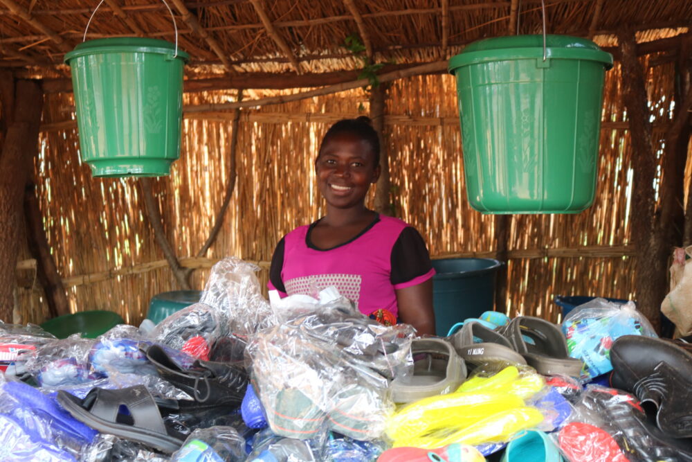 A woman vendor sells shoes and other items in the Kasese Trading Post