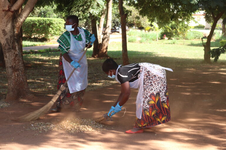 Two of the committee members clean up leaves from the campus.