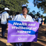 Orant Nurse holds a purple and blue sign on International Nurse's Day