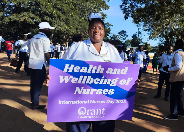 Orant Nurse holds a purple and blue sign on International Nurse's Day