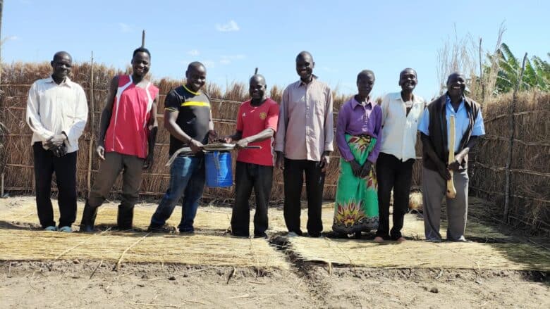 A team of people standing in front of a grass fence