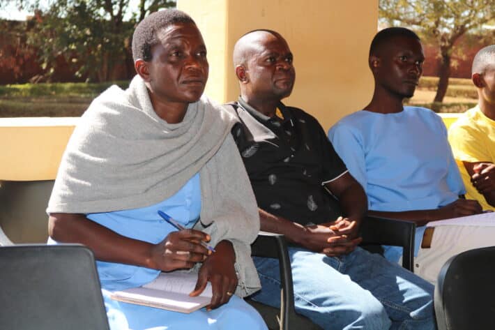 Three people sitting in chairs looking to a speaker who is not pictured