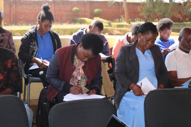 Several people sitting in chairs taking notes in notebooks