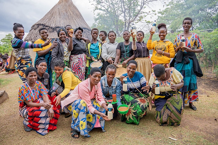 A group of African women stand together with their foods that they have cooked.