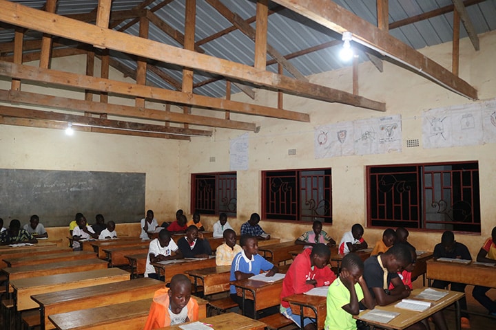 Students in Malawi study under the glow of a solar powered light.