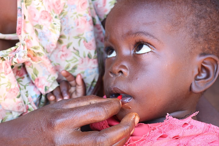 An African Baby receives vitamin A supplementation through a small ampule through its mothers hand.