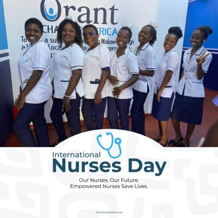 A line of nurses stand together in uniform in front of a wall that says Orant Charities Africa.