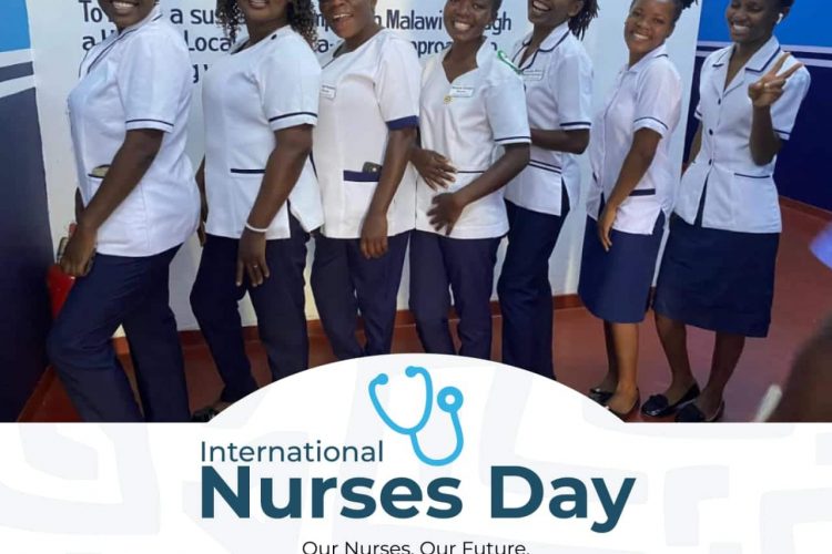 A line of nurses stand together in uniform in front of a wall that says Orant Charities Africa.