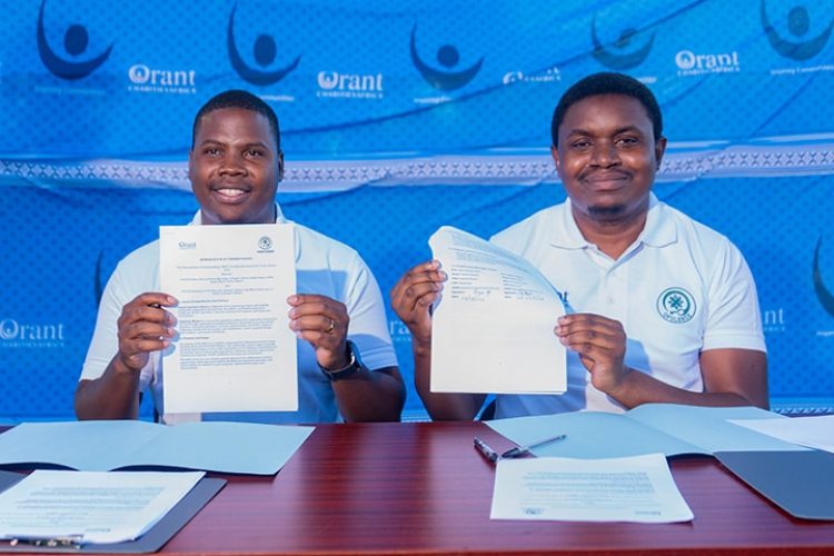 The two directors of Orant Charities Africa and Opulence Malawi hold up copies of the memorandum of understanding that they have signed. They are young black men with short hair and wearing white shirts.