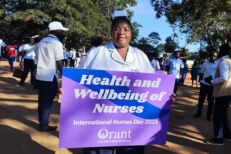 Orant Nurse holds a purple and blue sign on International Nurse's Day