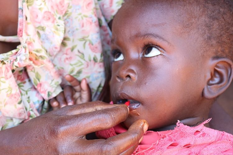 An African Baby receives vitamin A supplementation through a small ampule through its mothers hand.
